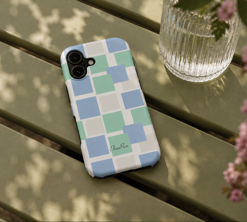 A phone case with a geometric checkered pattern in pastel blue, green, and white squares.