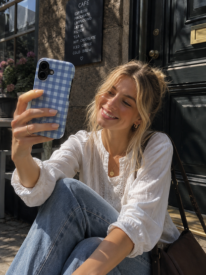 Woman holding a blue gingham tough phone case