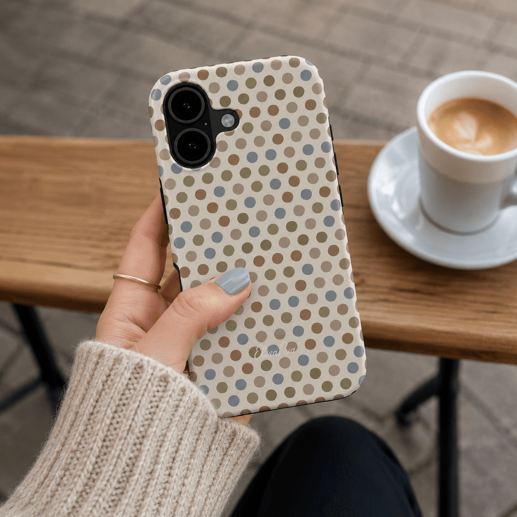 A hand holding a cute phone case with a neutral multicolor polka dot pattern.