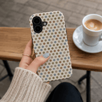A hand holding a cute phone case with a neutral multicolor polka dot pattern.