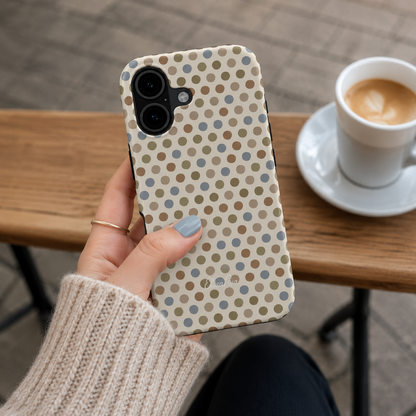 A hand holding a cute phone case with a neutral multicolor polka dot pattern.