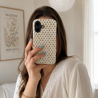 Tough phone case with a beige background and a pattern of neutral brown, gold, and light blue polka dots. 